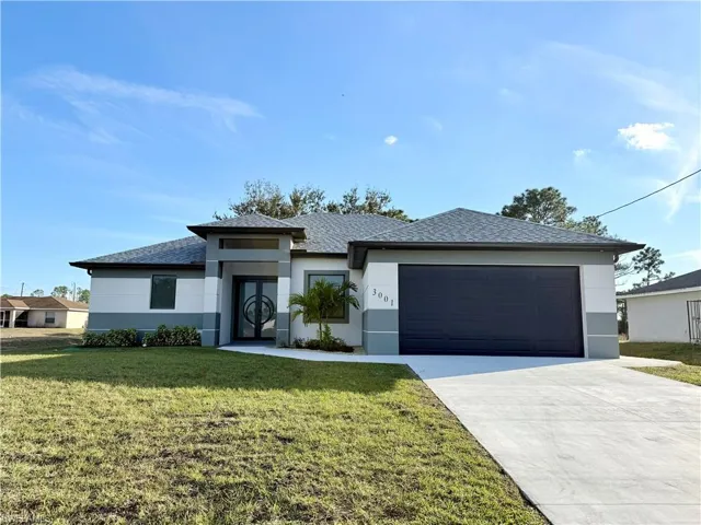 Prairie-style home with a front yard, stucco siding, driveway, an attached garage, and a shingled roof