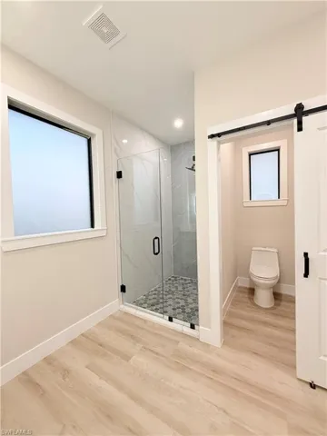 Full bath featuring wood finished floors and a marble finish shower