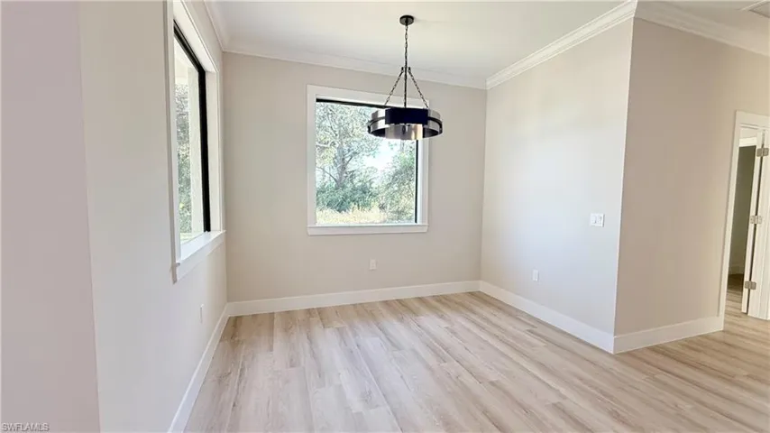 Unfurnished dining area featuring crown molding and light wood-style flooring