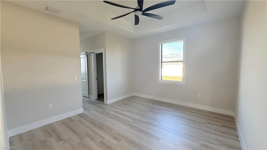 Master Bedroom featuring light wood-style flooring, a raised ceiling, and ceiling fan