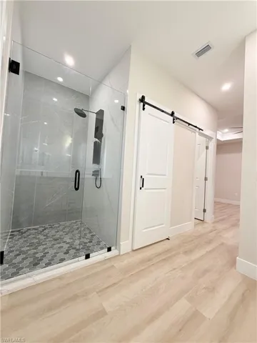 Full bathroom featuring wood finished floors, a shower stall, and recessed lighting