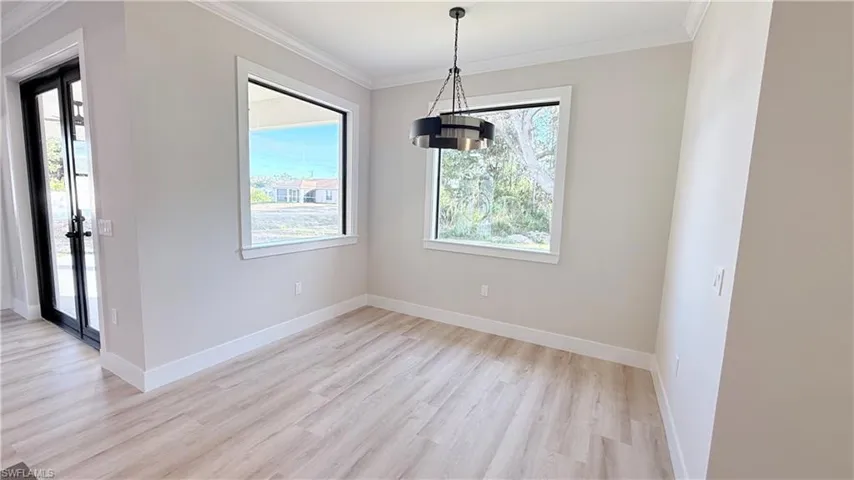 Unfurnished dining area with crown molding, light wood finished floors, and suspended lighting
