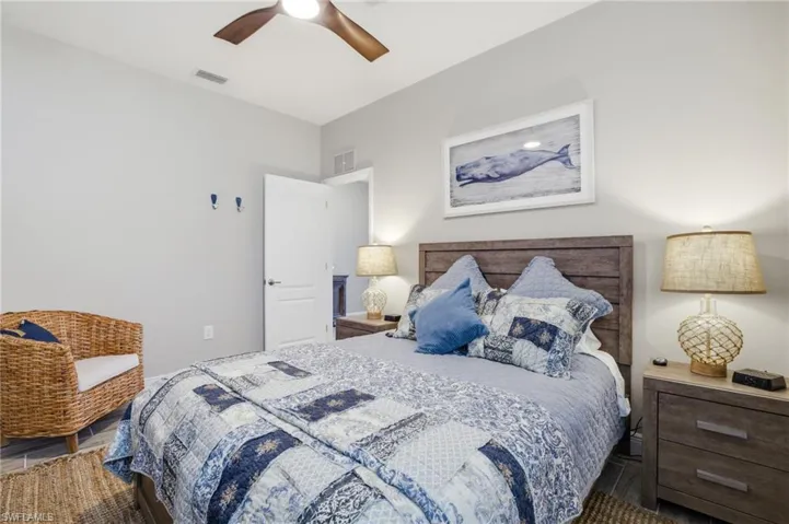 Bedroom featuring a wood-finish headboard, matching nightstands, and a ceiling fan with integrated lighting