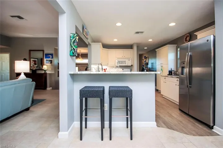 Breakfast bar. granite countertops, light hardwood / wood-style floors, and kitchen peninsula
