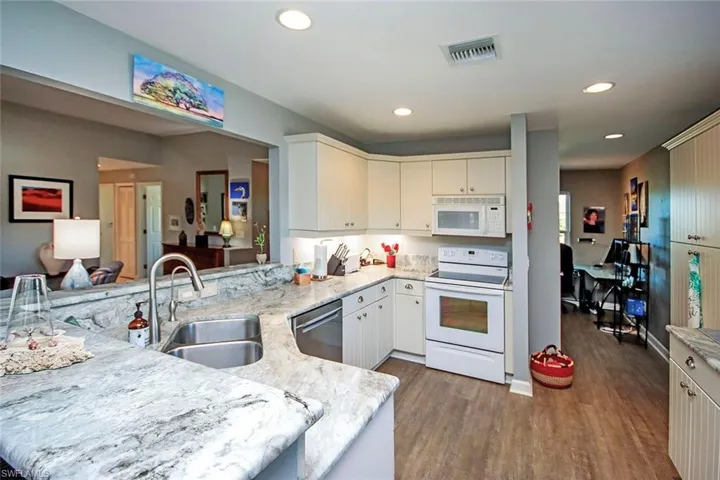 Kitchen with dark hardwood / wood-style flooring, sink, white appliances, and kitchen peninsula