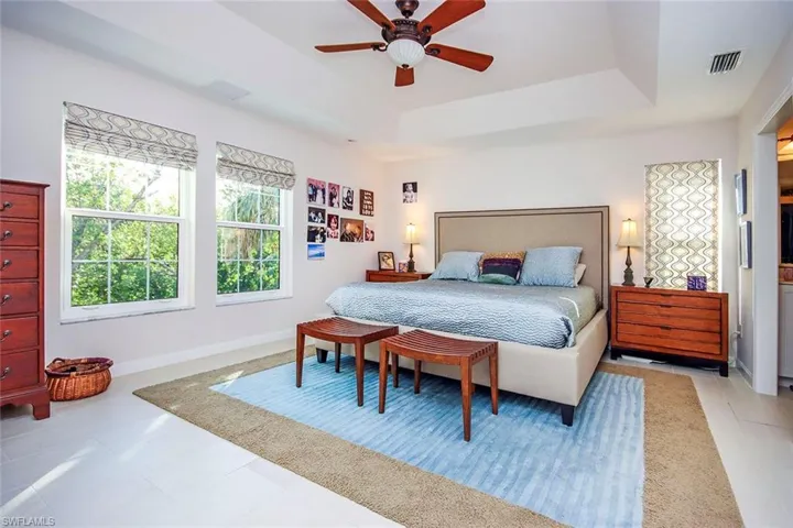 Tiled bedroom with a raised ceiling and ceiling fan