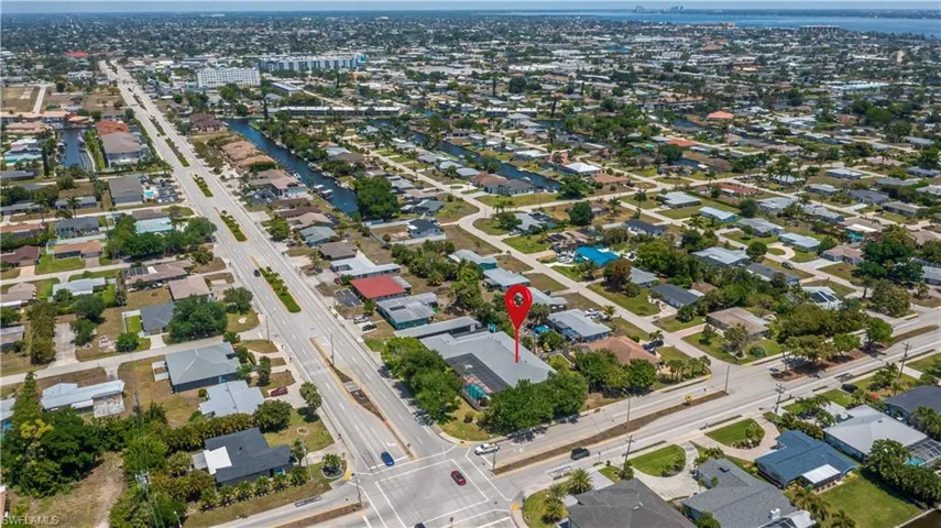 Aerial perspective showcasing a large property with a light-colored roof situated on a prominent corner lot