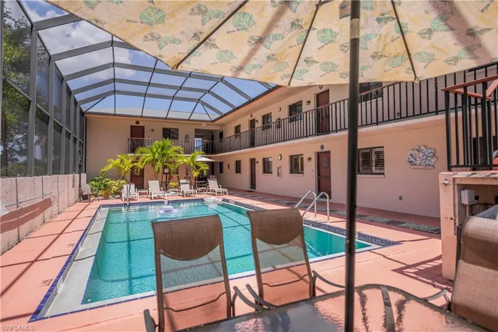 Screen-enclosed courtyard pool area featuring a rectangular swimming pool with integrated steps and handrails, surrounded by coral-colored pavers