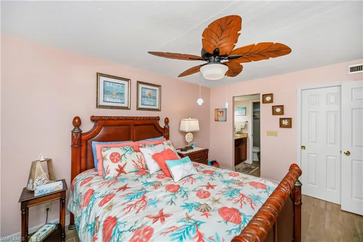 Bedroom featuring a wood-finish bed frame, ceiling fan with wood-look blades, and white bi-fold doors