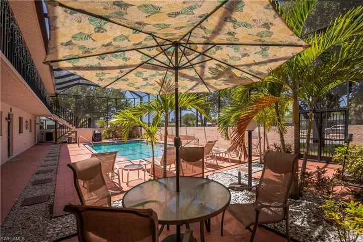 Screened outdoor pool area featuring a paved patio and mature palm trees