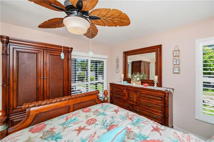 Room featuring a decorative ceiling fan with leaf-shaped blades, light-toned wall paint, and white framed windows