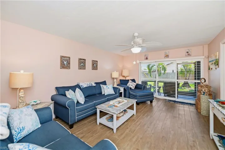 Living area featuring wood-finish flooring, a white ceiling fan, and sliding glass doors