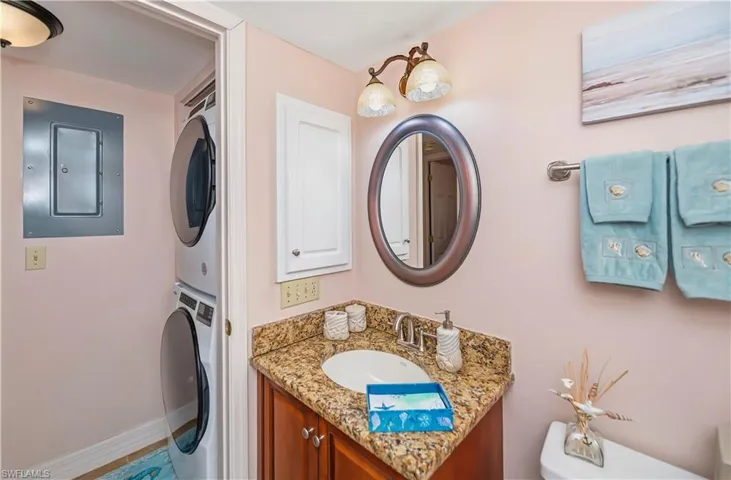 Bathroom featuring a vanity with a granite-style countertop, an oval mirror, and a two-light fixture