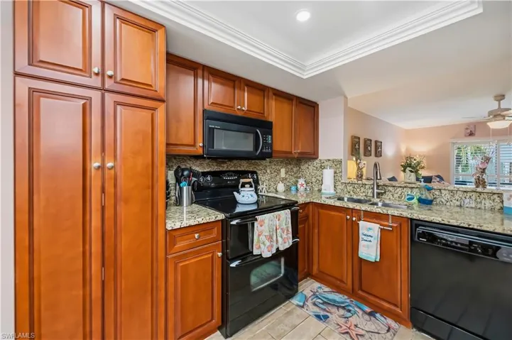 Kitchen featuring granite countertops, wood-finish cabinetry, black appliances, and recessed lighting