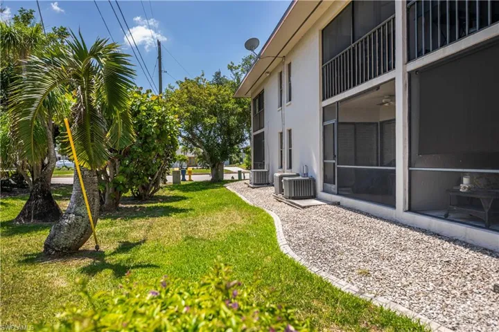 Exterior featuring a white stucco facade, multiple screened-in enclosures, and ground-level air conditioning units