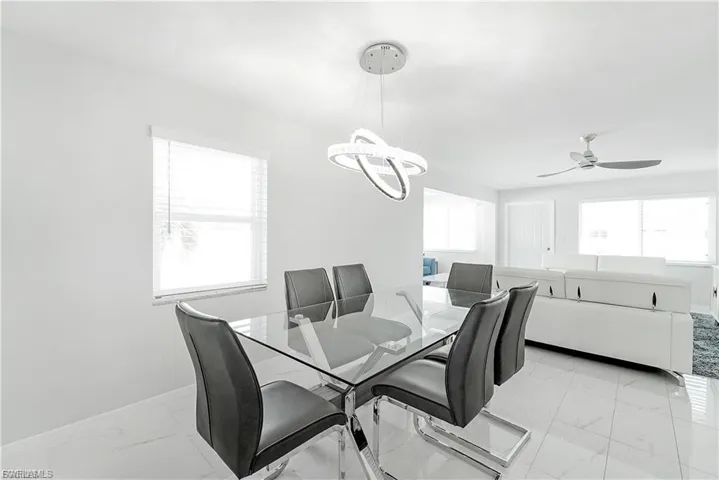 Dining room featuring light marble finish flooring, a chandelier, and ceiling fan
