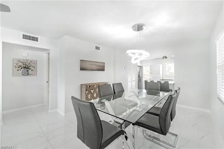 Dining room featuring light marble finish flooring, a chandelier, and a ceiling fan