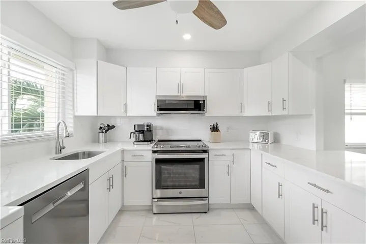 Kitchen featuring appliances with stainless steel finishes, light marble finish floors, healthy amount of natural light, a ceiling fan, and recessed lighting