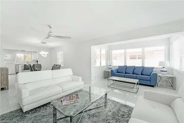 Living room featuring light marble finish flooring, ceiling fan, and a chandelier