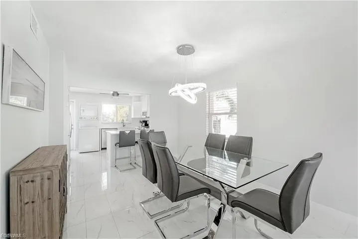 Dining space with light marble finish floors, a chandelier, and washer / clothes dryer