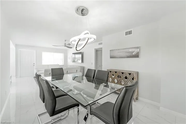 Dining area featuring a chandelier, light marble finish flooring, and a ceiling fan