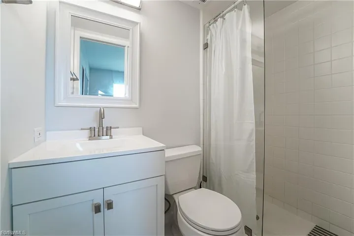 Full bath featuring tiled shower and vanity