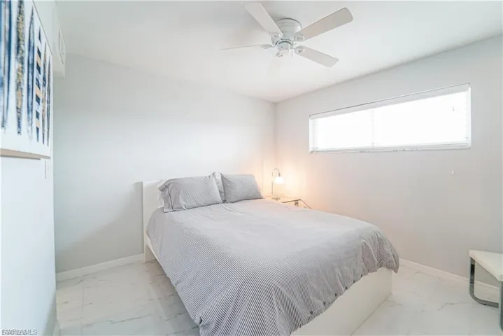 Bedroom featuring marble look tile flooring and ceiling fan