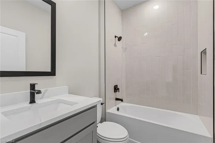 Kitchen featuring stainless steel appliances, wood tiled floors, gray cabinets, backsplash, and a center island with sink