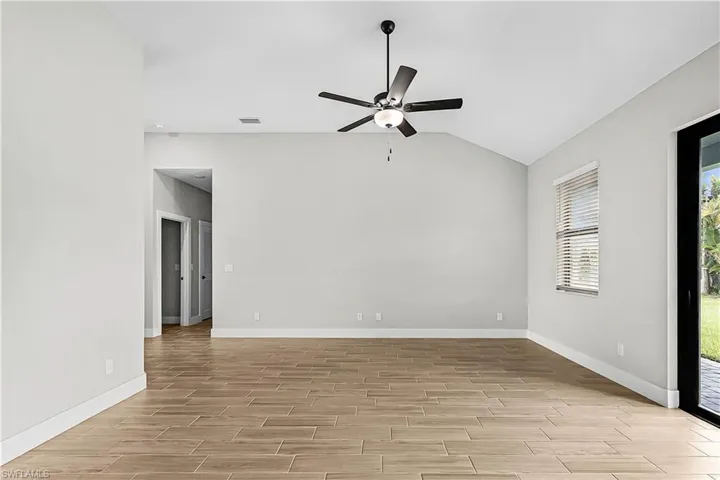 Empty room featuring lofted ceiling, wood finish floors, and ceiling fan