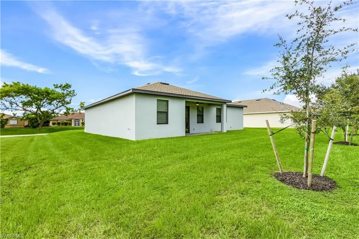 Rear view of house featuring a yard, stucco siding, a patio area, and a shingled roof
