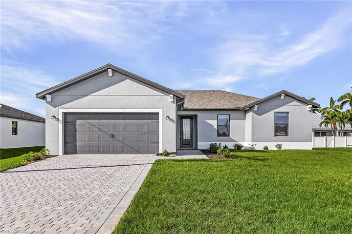Ranch-style house with a front yard, concrete driveway, stucco siding, and a garage
