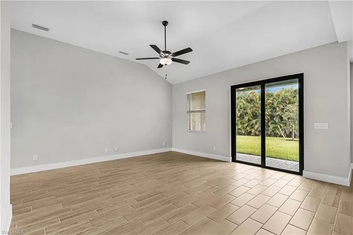 Spare room with lofted ceiling, wood tiled floors, and a ceiling fan