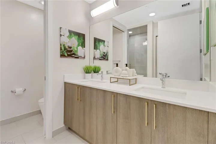 Bathroom with tile patterned floors, vanity, toilet, and an glass enclosed shower