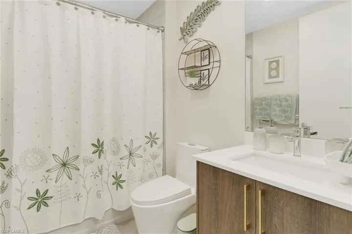 Bathroom with vanity, toilet, and curtained shower