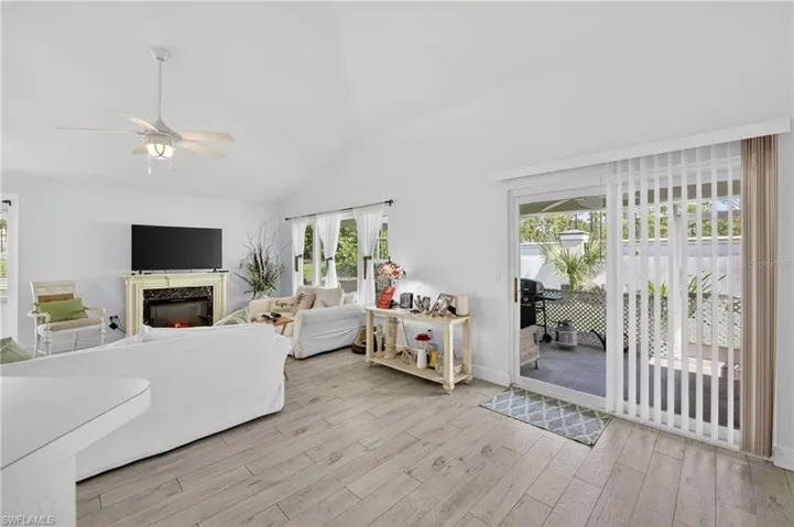 Spacious living area featuring light wood-finish flooring and a vaulted ceiling with a ceiling fan