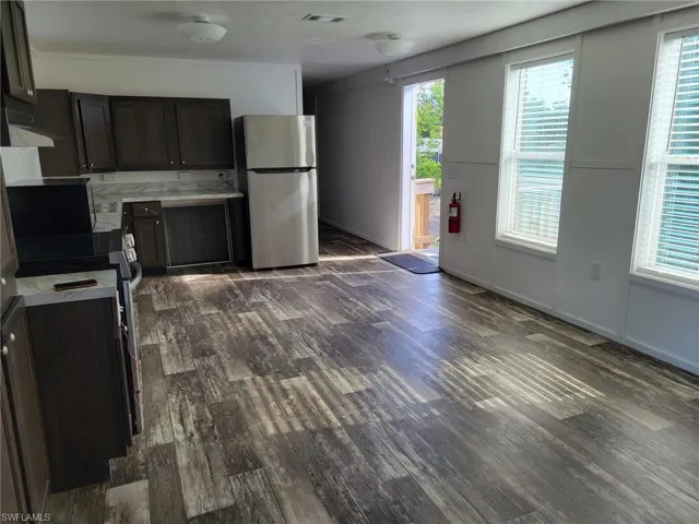 Kitchen with dark wood-style flooring, light countertops, freestanding refrigerator, visible vents, and electric stove