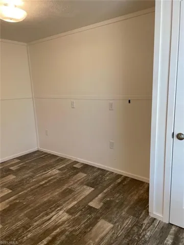 Unfurnished room with dark wood-style flooring and baseboards