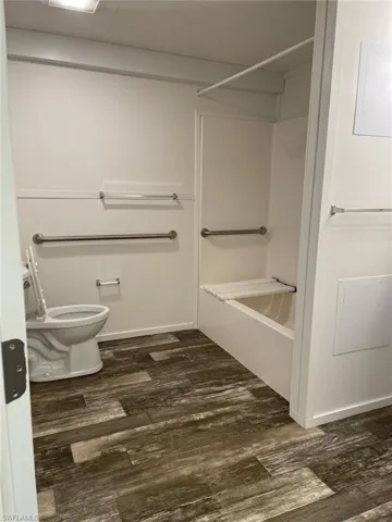 Bathroom featuring toilet, baseboards, wood finished floors, and shower / bathtub combination