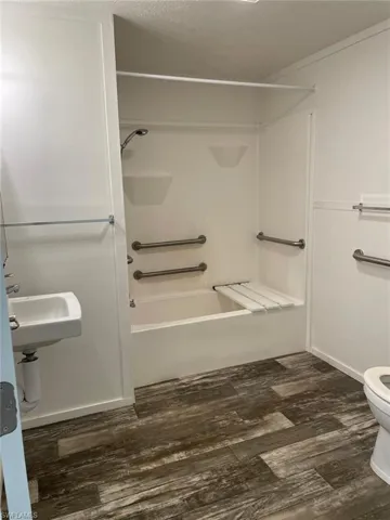 Bathroom featuring shower / bath combination, a sink, toilet, and wood finished floors