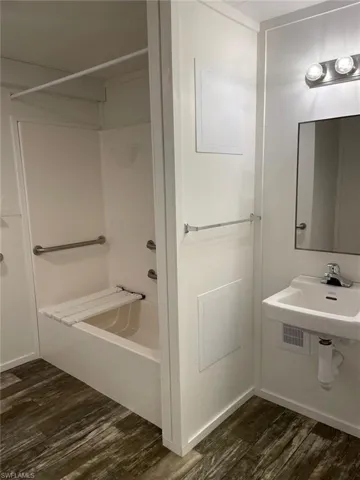 Bathroom with wood finished floors, a sink, and shower / washtub combination