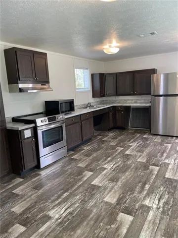 Kitchen featuring a textured ceiling, appliances with stainless steel finishes, and visible vents