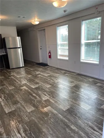 Unfurnished living room featuring dark wood-style flooring, visible vents, and a textured ceiling