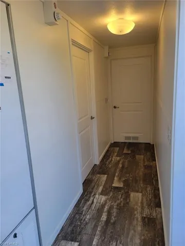 Corridor with visible vents, a textured ceiling, and dark wood finished floors