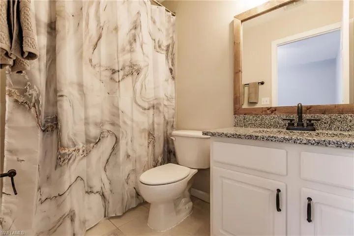 Bathroom with tile flooring, toilet, and vanity with extensive cabinet space