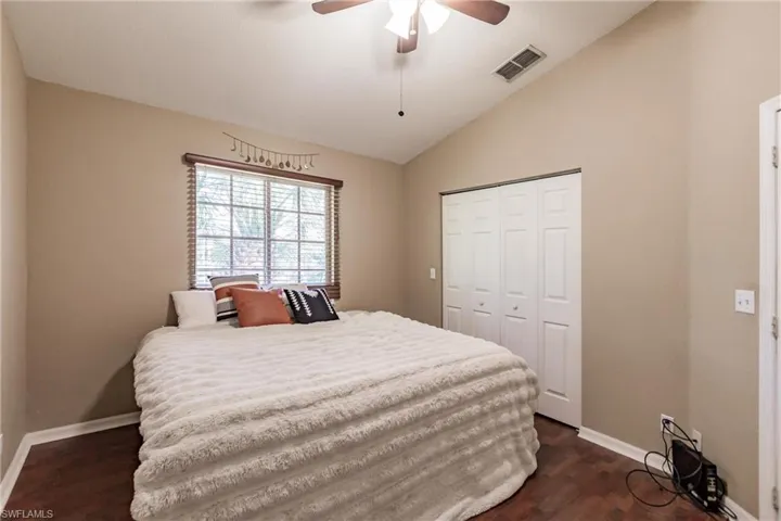 Bedroom with dark hardwood / wood-style floors, ceiling fan, a closet, and vaulted ceiling