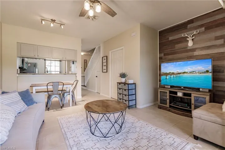 Tiled living room with sink, wooden walls, ceiling fan, and rail lighting