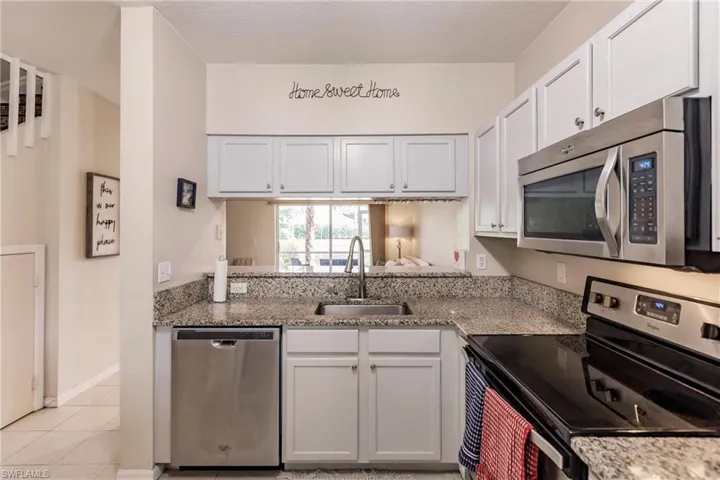 Kitchen featuring white cabinetry, sink, light tile floors, and stainless steel appliances