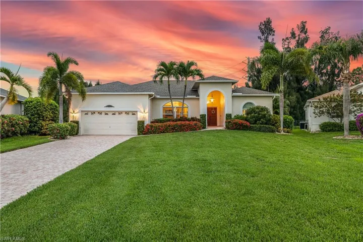 View of front of property with a garage and a yard