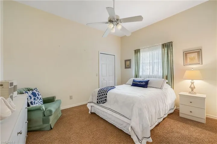 Carpeted bedroom featuring ceiling fan and a closet