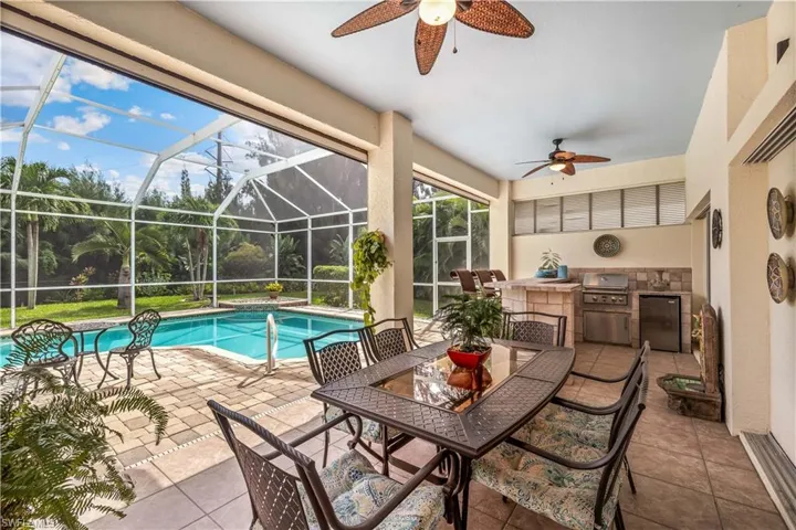 View of pool with area for grilling, grilling area, a patio, ceiling fan, and glass enclosure